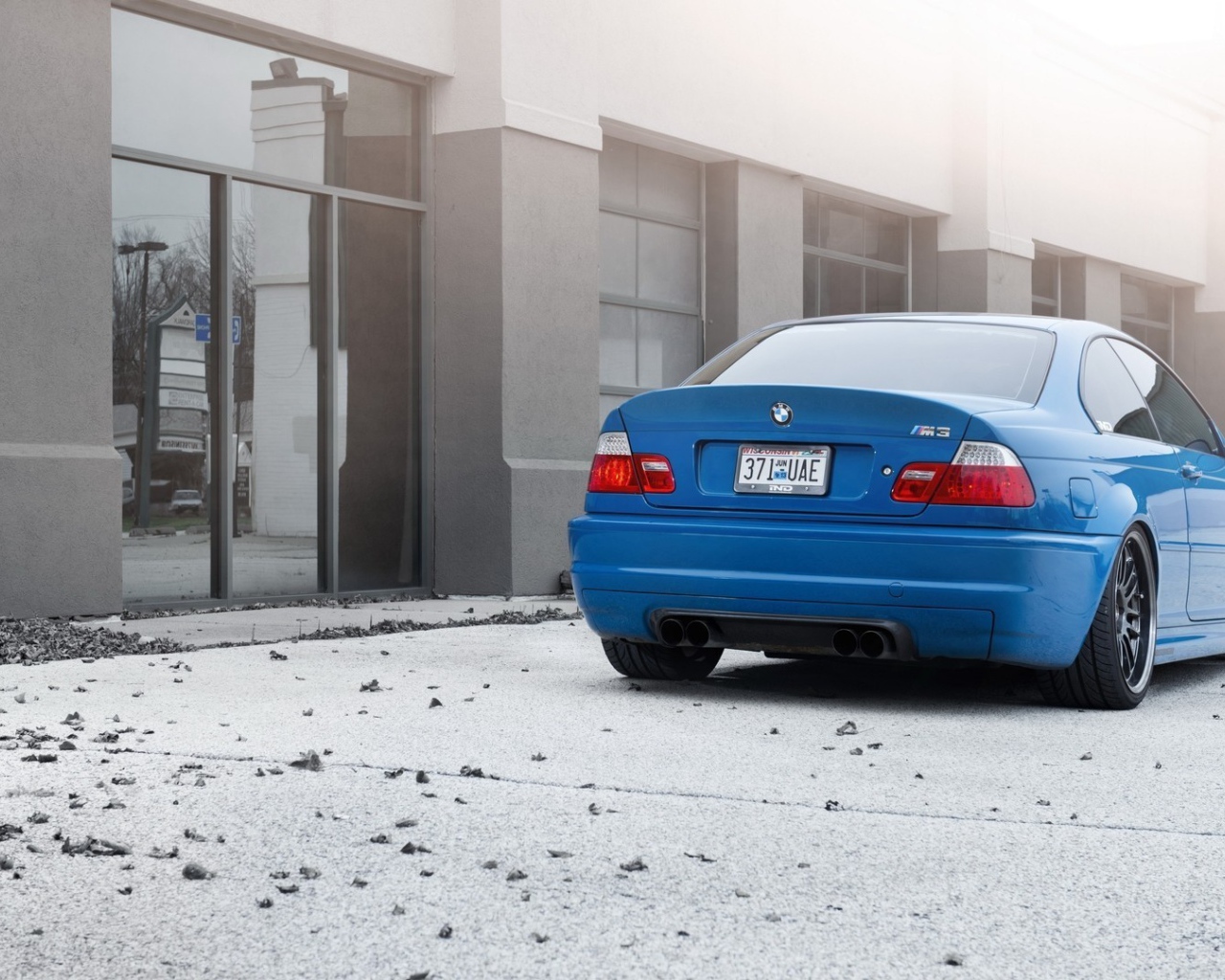 Голубой BMW на бетонной площадке у дома