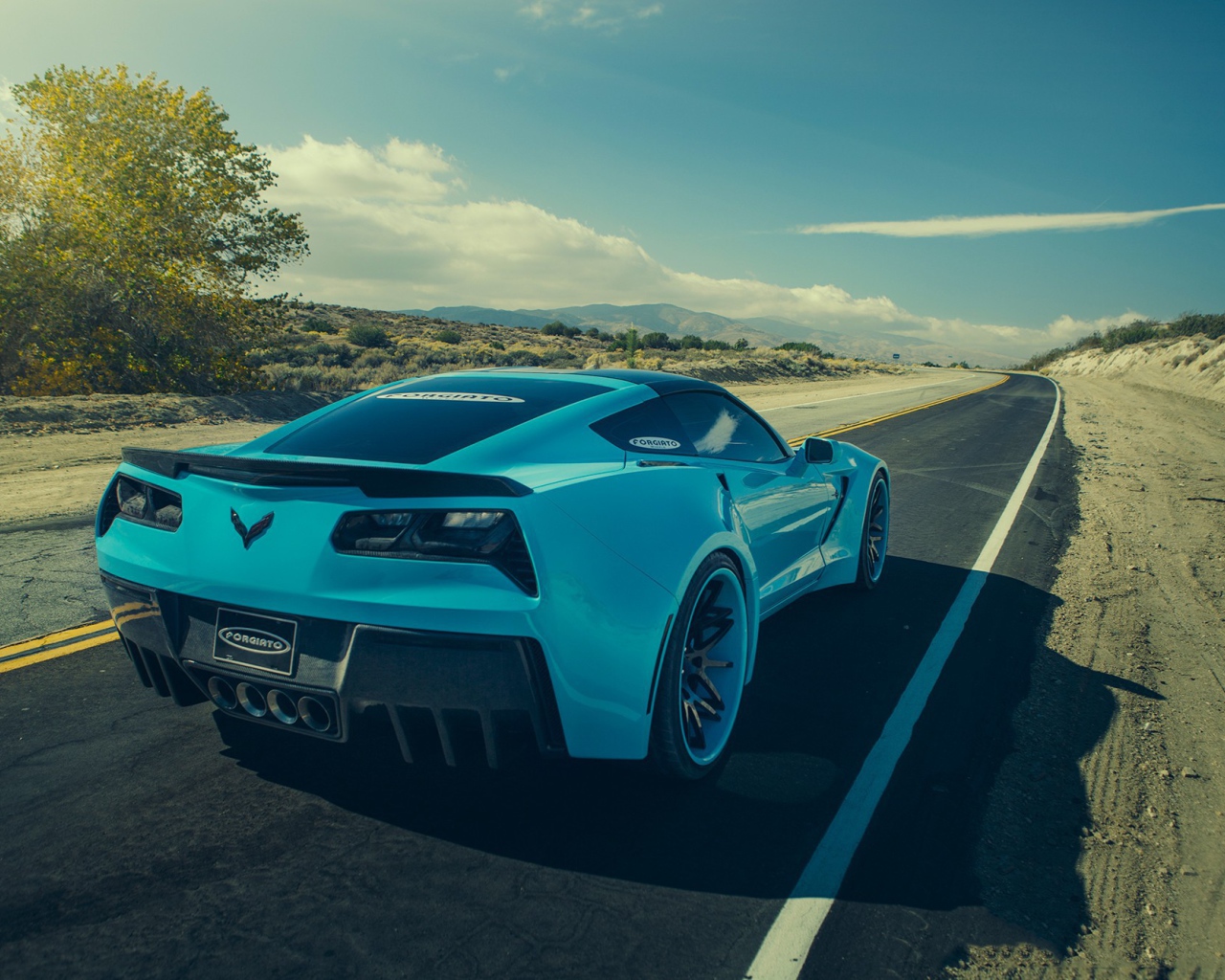 Голубой спортивный Chevrolet на шоссе в жаркой пустыне