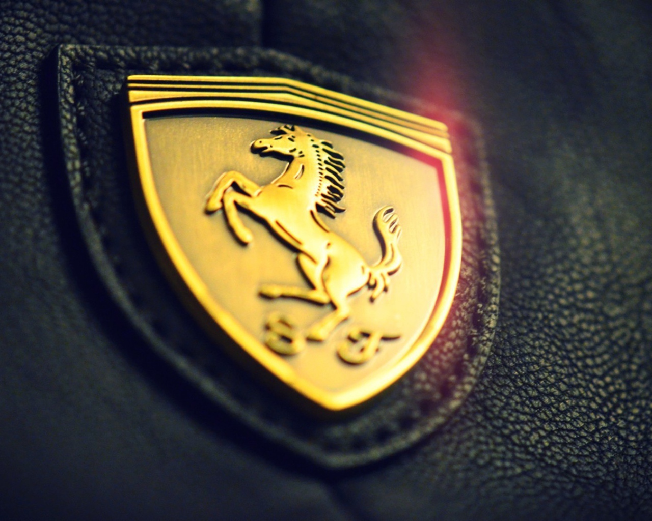 Золотой символ Ferrari на черной коже