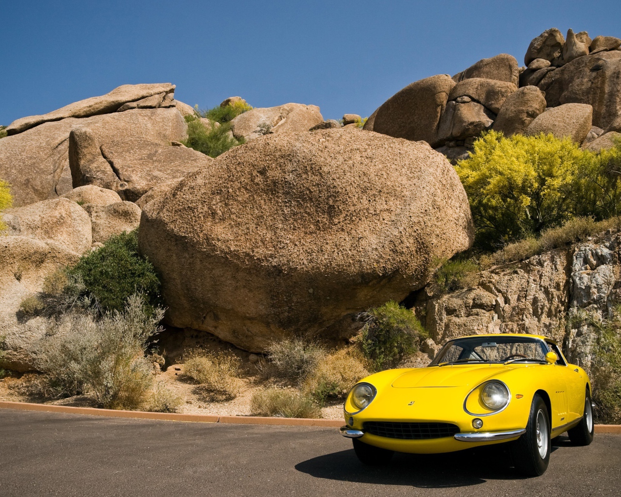 Старый желтый Ferrari у большого камня