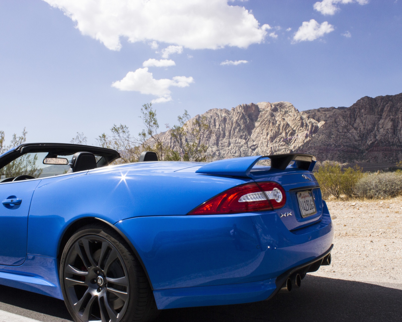 Голубой кабриолет Jaguar на фоне гор