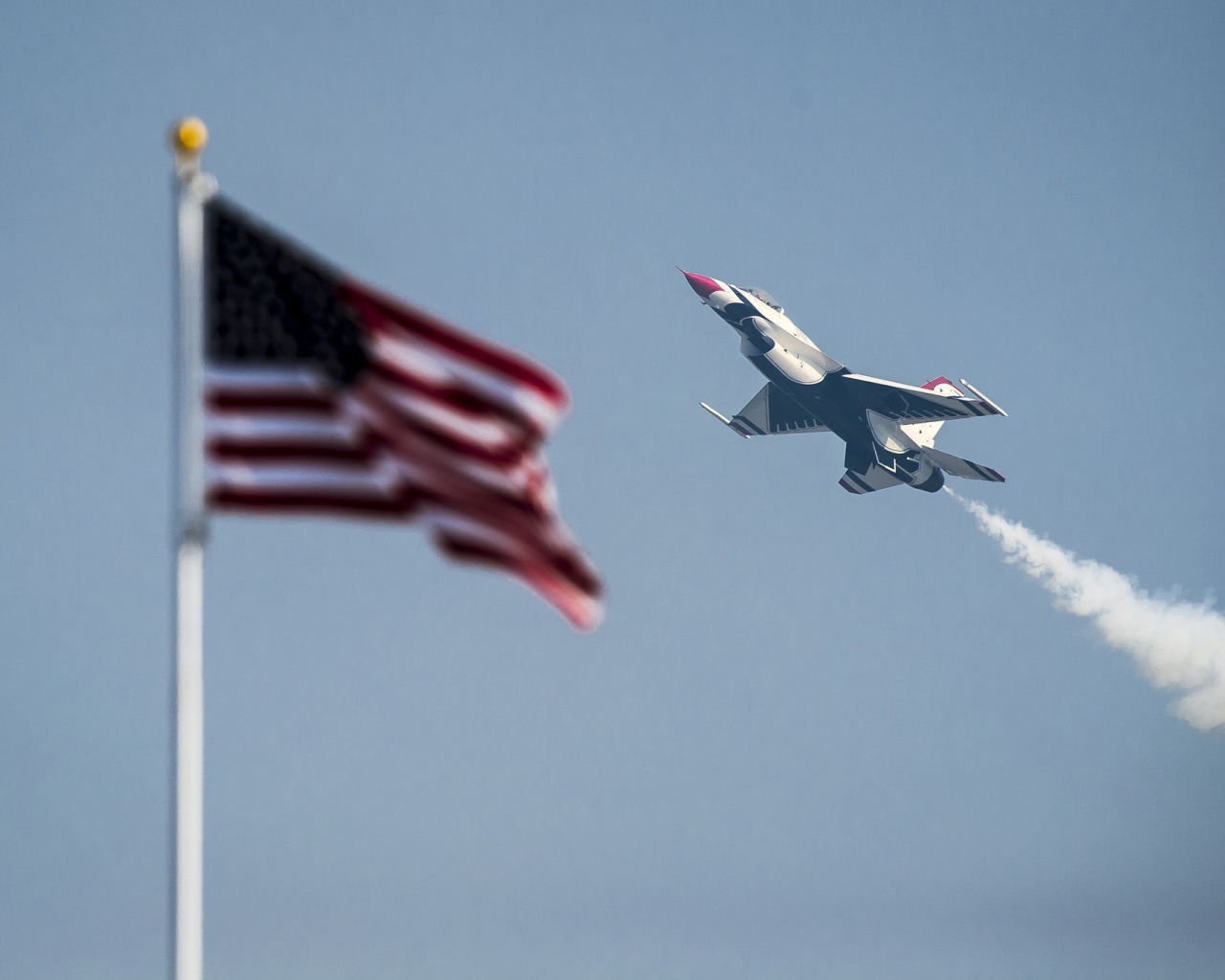 Истребитель F-16 Fighting Falcon пролетает над флагом США