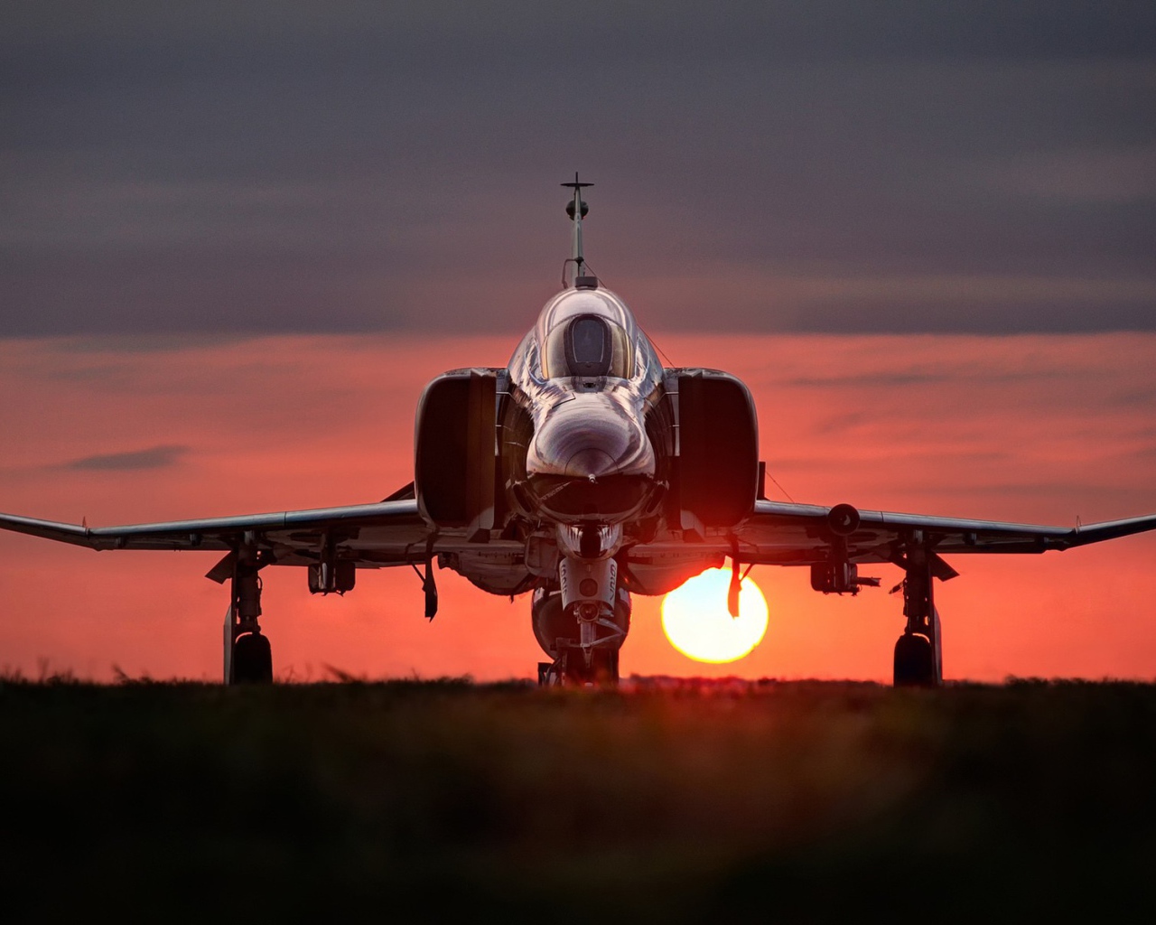 Истребитель F-4 Phantom II стоит на фоне заката
