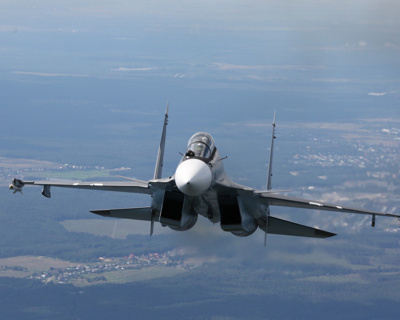 Самолет СУ-27 летит над городом