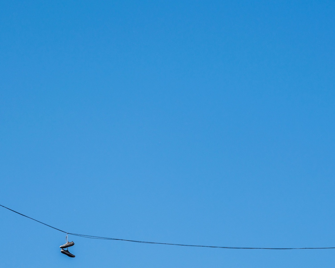 Кеды висят на проводе на фоне голубого неба