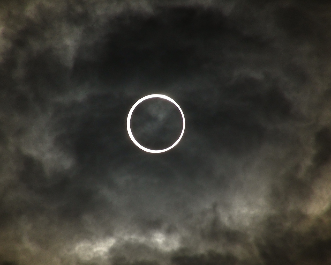 Белый круг на фоне темных облаков