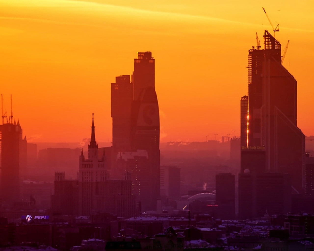 Стройка небоскребов на фоне оранжевого неба