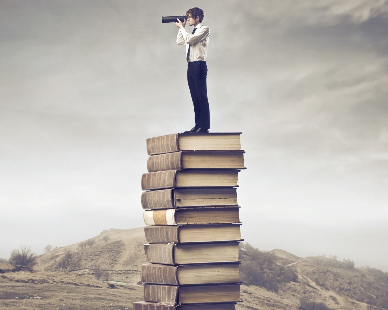 Мужчина с подзорной трубой на стопке книг