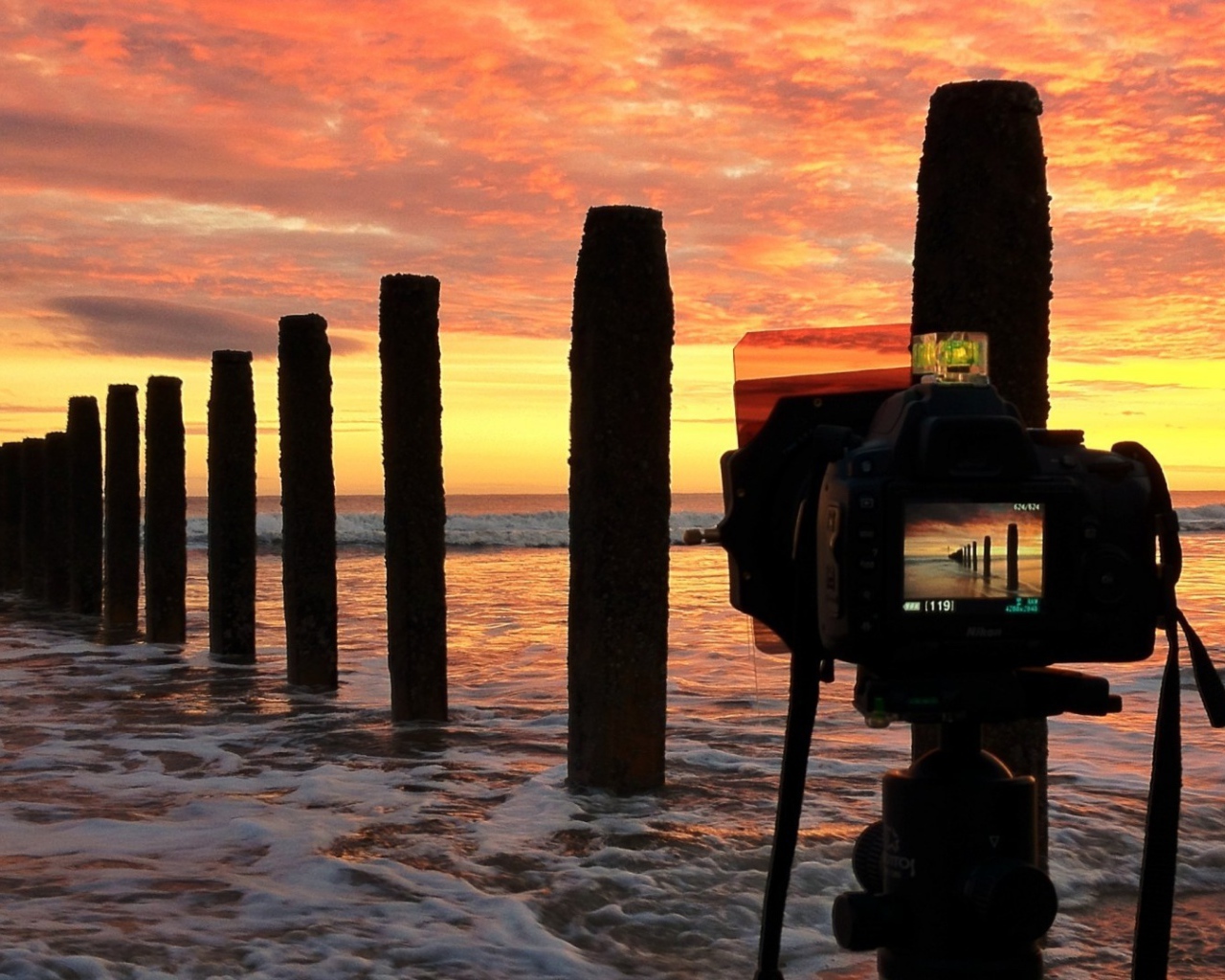 Фотограф снимает закат на берегу моря