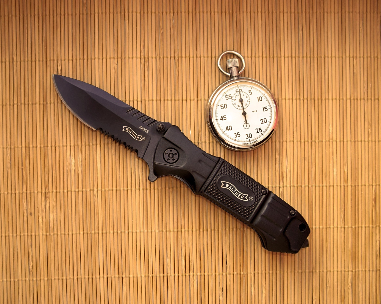 Часы и нож на бамбуковом коврике