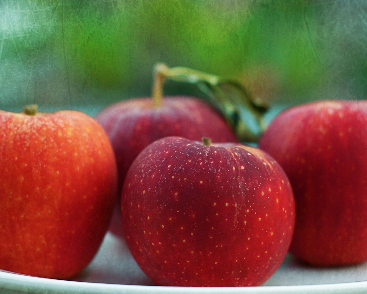 Четыре красных яблока на тарелке