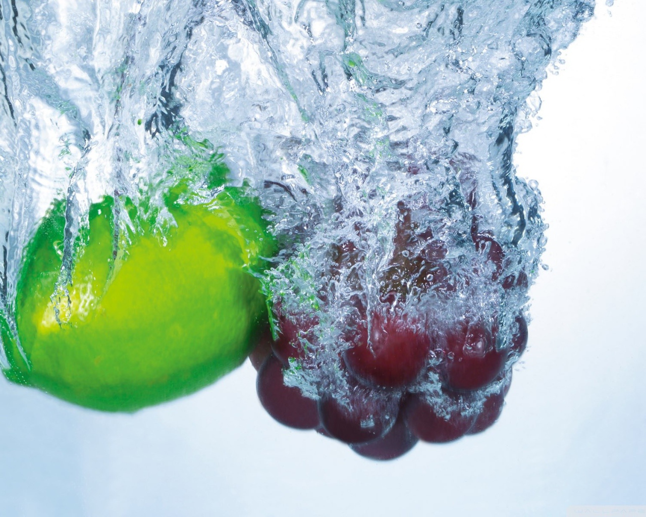 Зеленый лимон и кисть винограда в воде