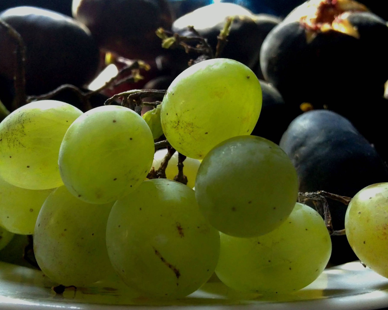 Крупный белый и черный виноград на тарелке