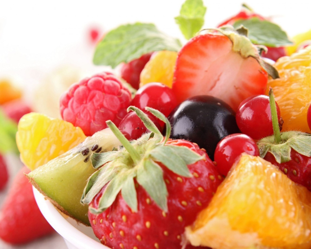 Кусочки спелых фруктов и ягоды на тарелке
