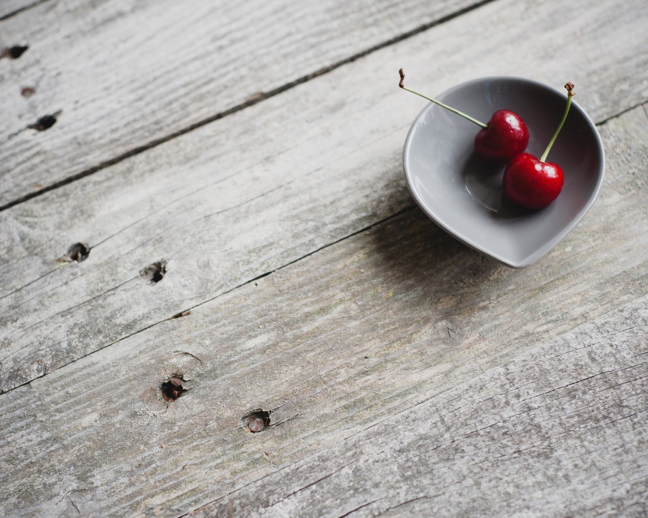 Две красных вишни в керамической чашке