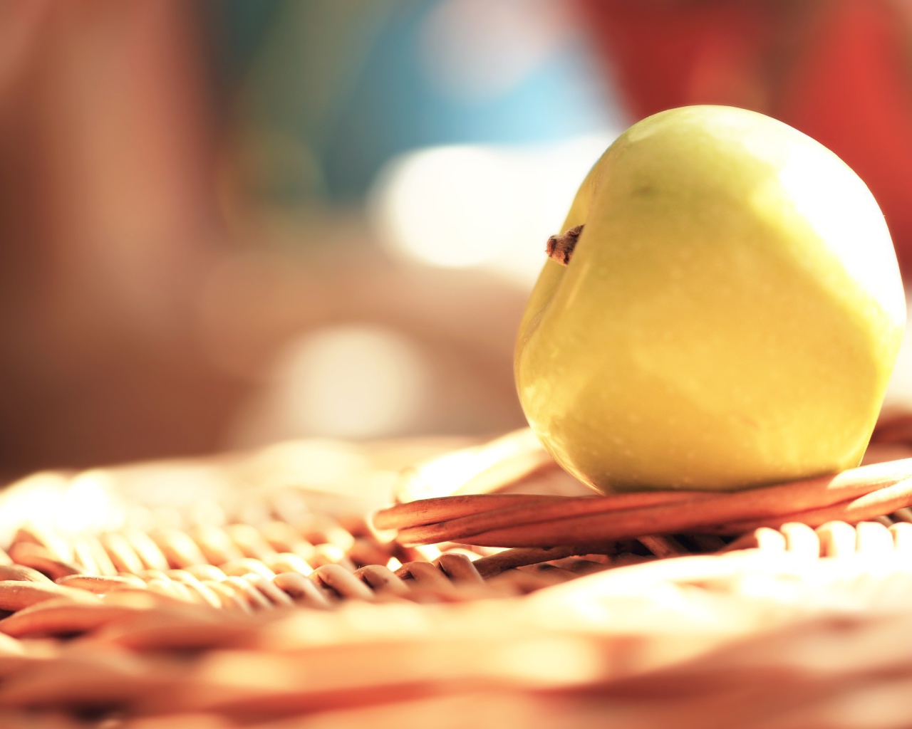 Белое яблоко на плетеной подставке