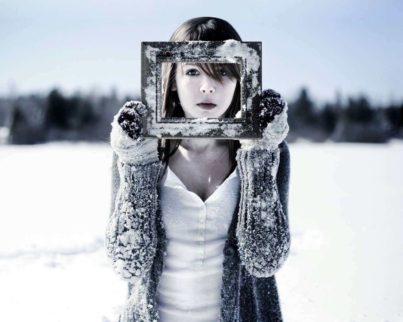 Девушка держит в руках фоторамку в снегу