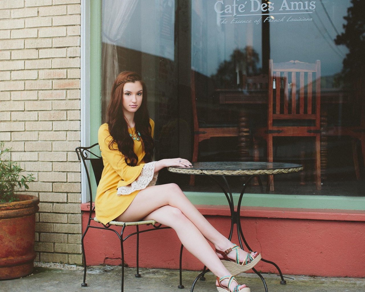 Девушка сидит за столиком уличного кафе