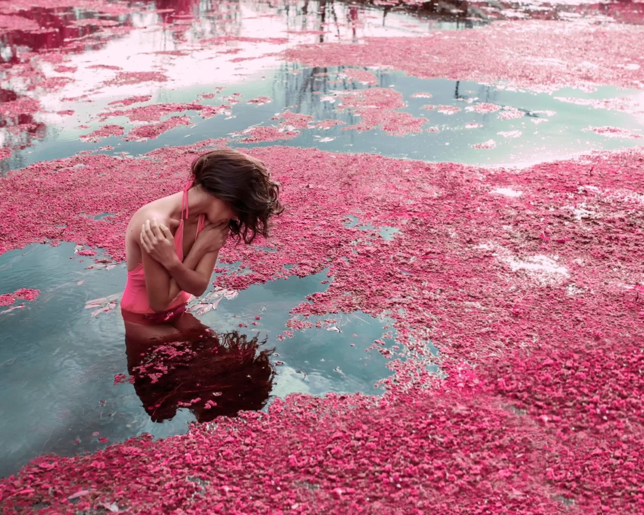 Девушка стоит в воде среди розовых лепестков