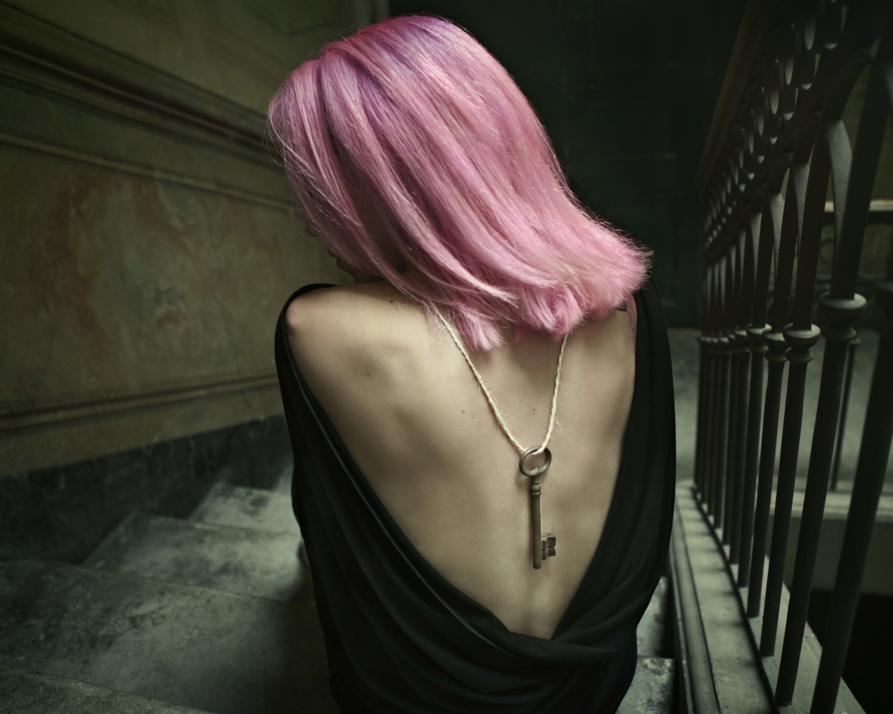 Девушка с розовыми волосами сидит на лестнице