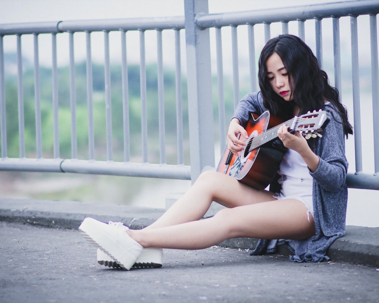 Азиатка брюнетка с гитарой на мосту