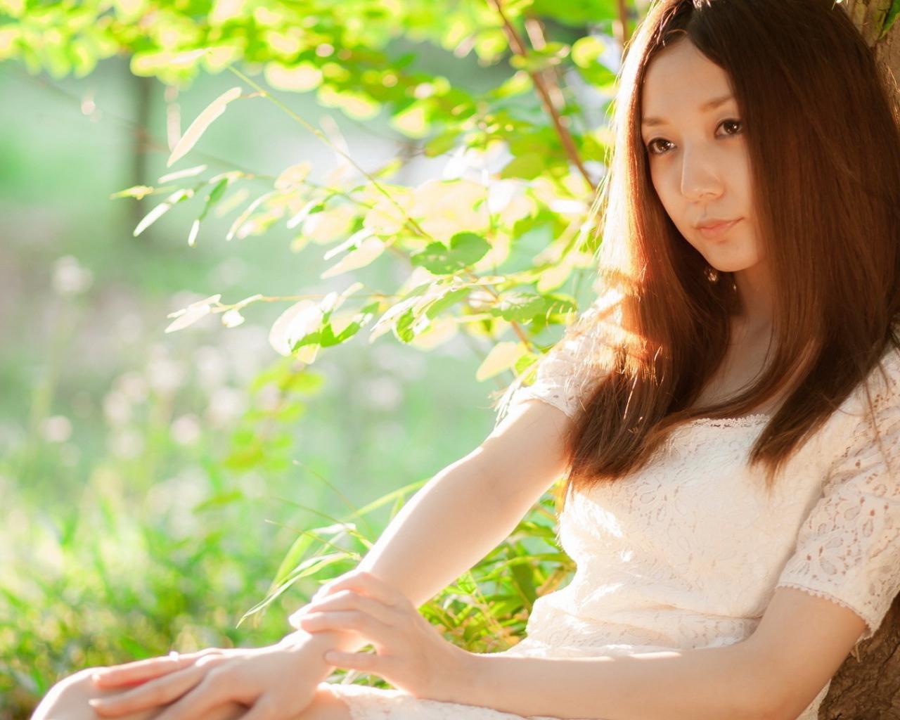 Азиатская девушка прислонилась спиной к дереву