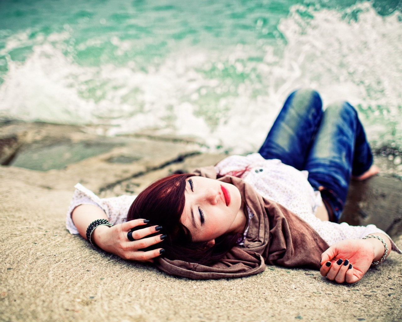 Босая девушка в джинсах лежит на набережной