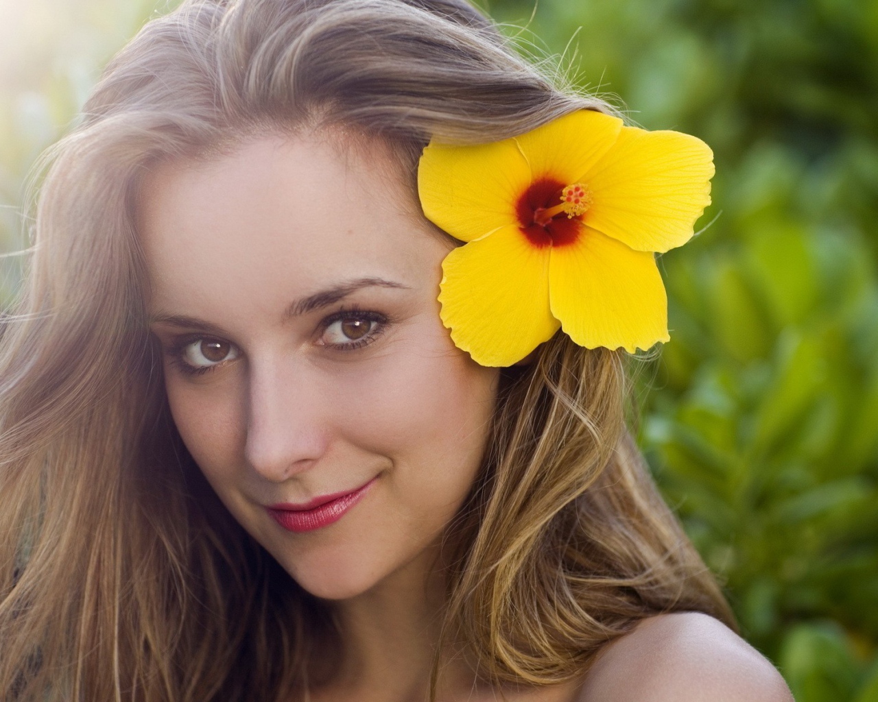 Большой желтый цветок в волосах у девушки
