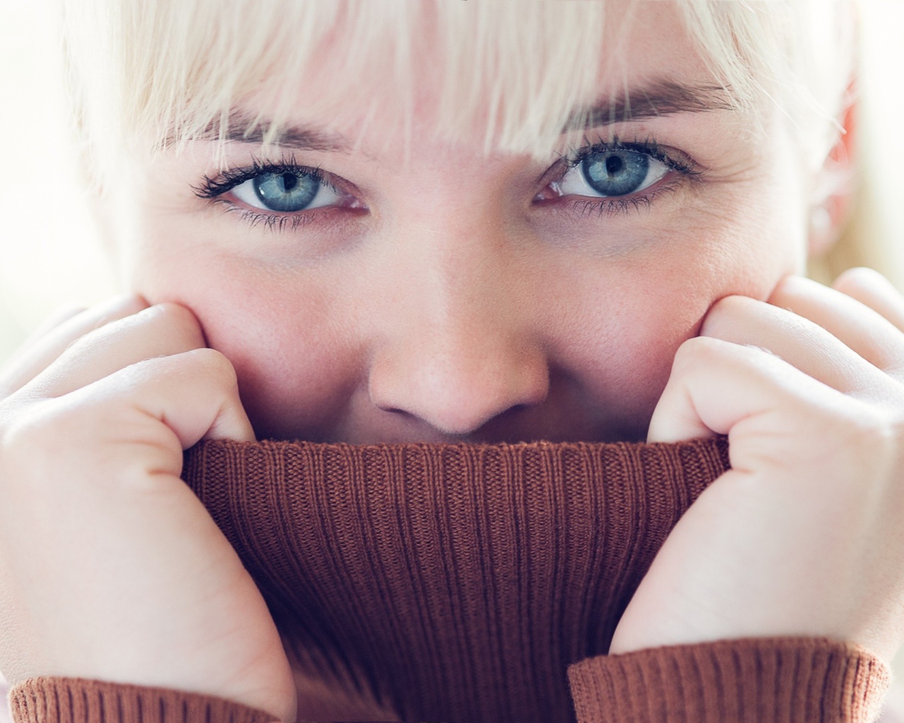 Блондинка прячет лицо в вороте свитера