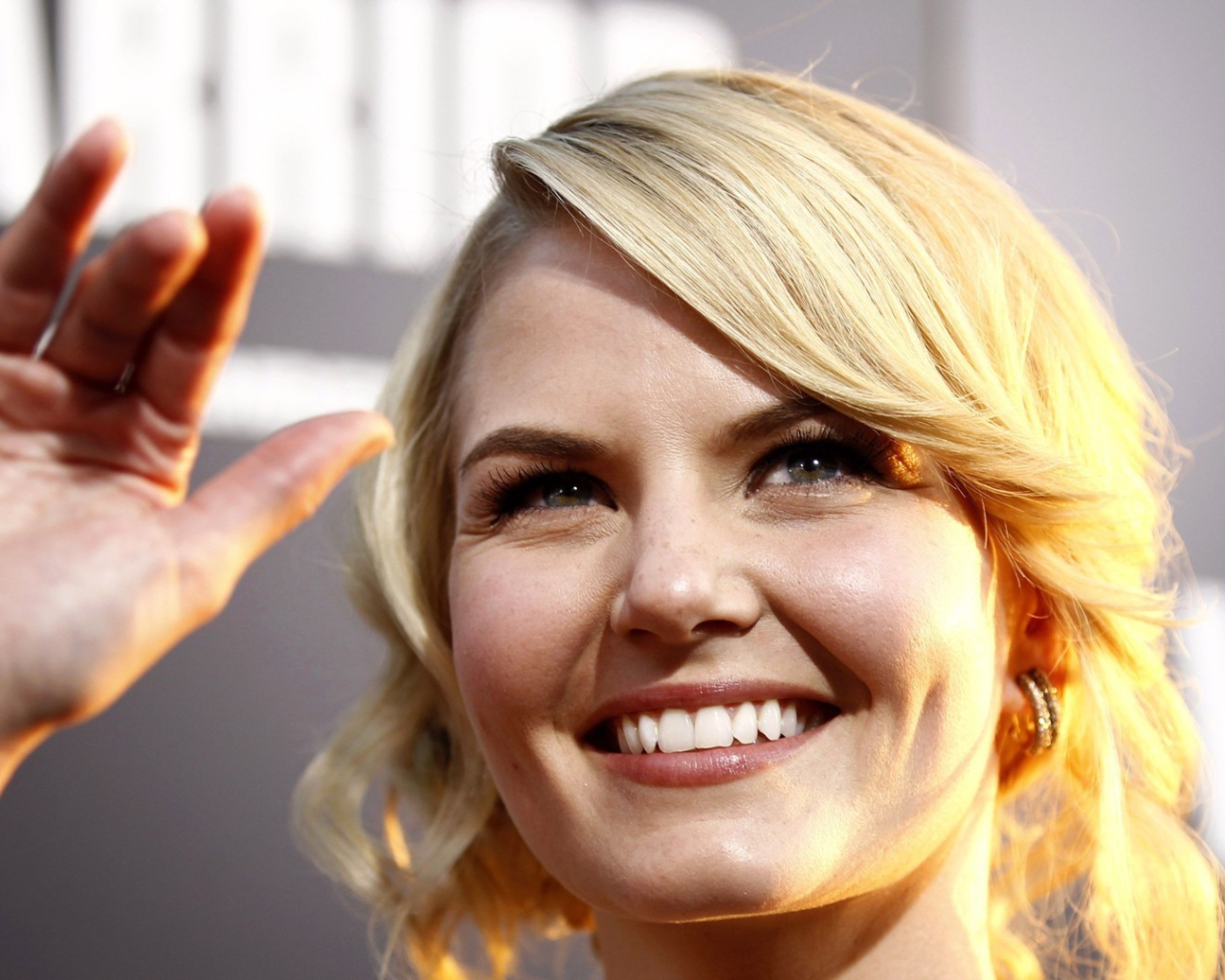 Блондинка улыбается и машет