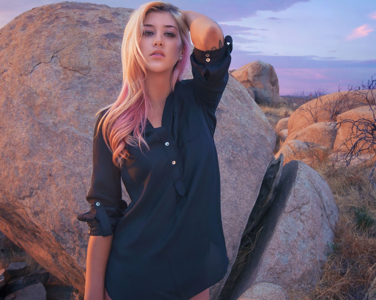 Блондинка стоит у большого валуна