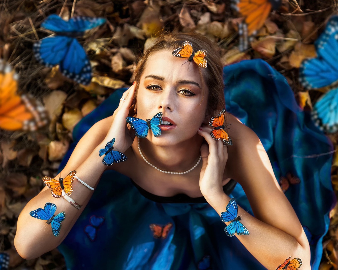 Голубые и оранжевые бабочки на девушке