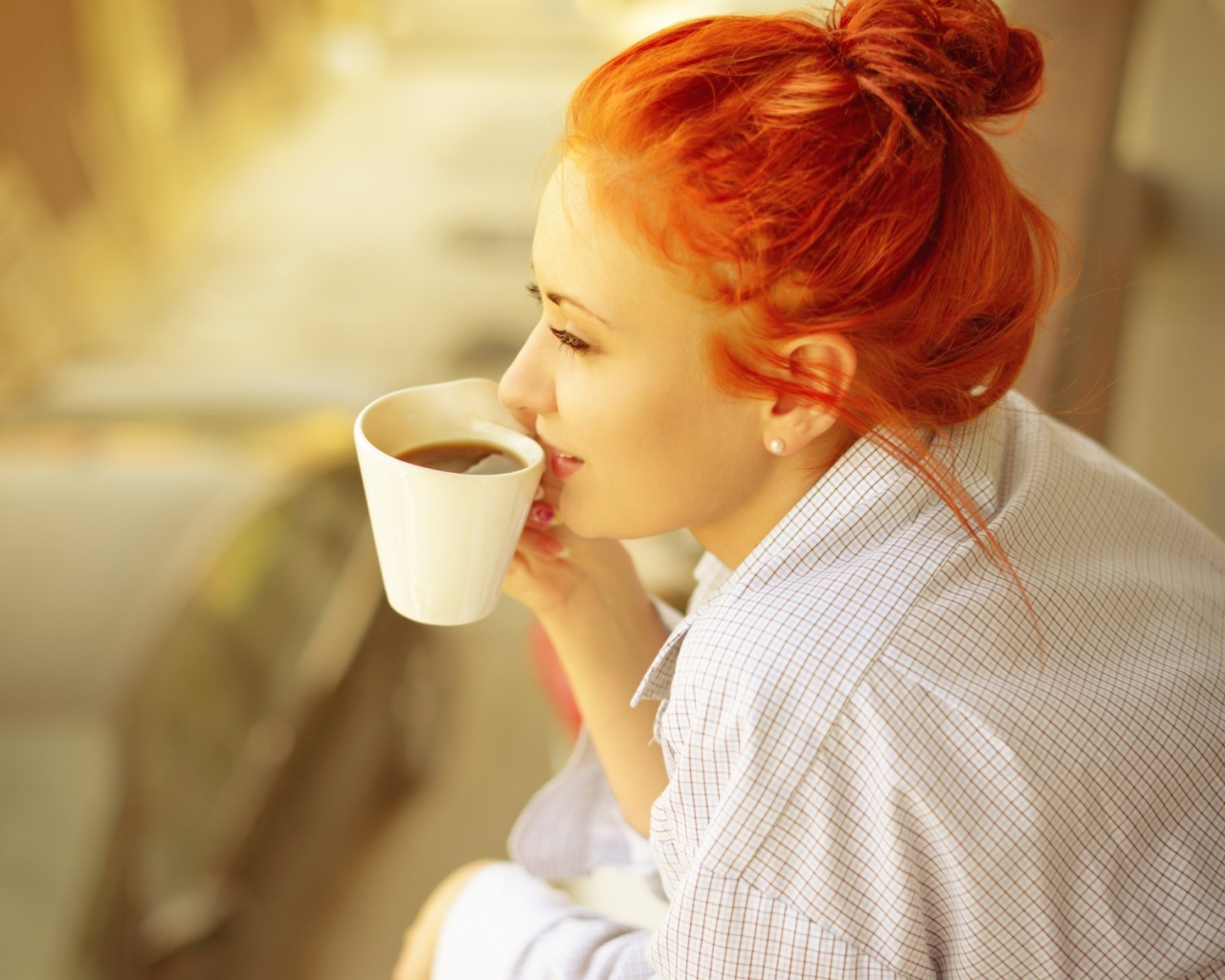 Ярко рыжая девушка в рубашке пьет кофе
