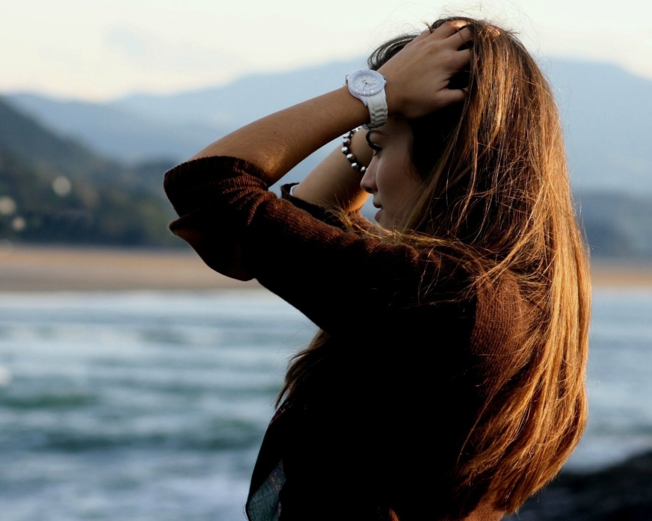 Шатенка с длинными волосами поправляет прическу