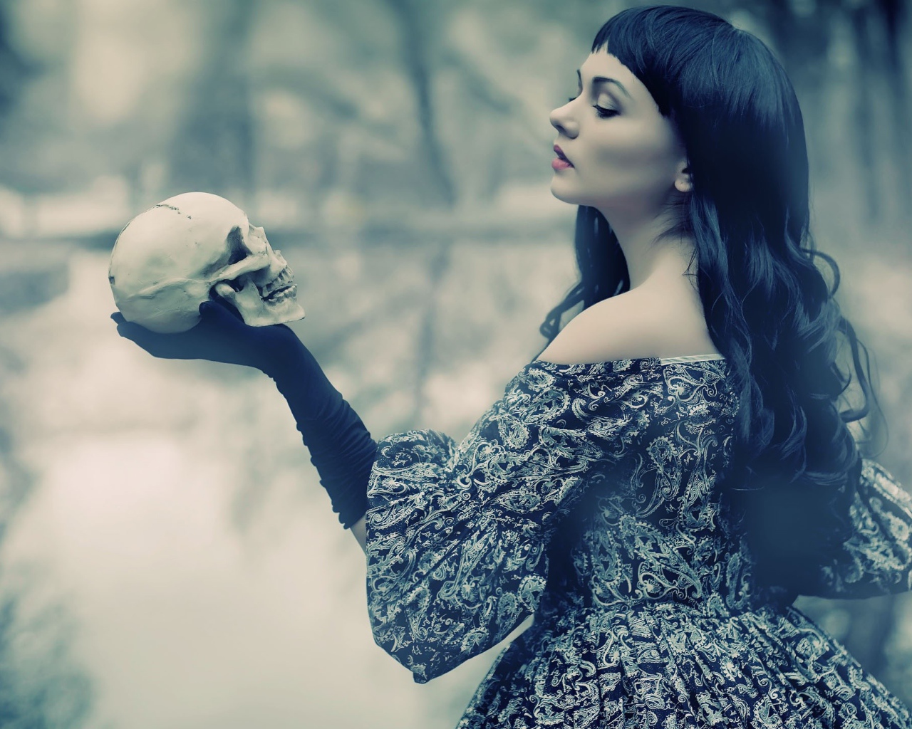 Брюнетка держит в руке череп