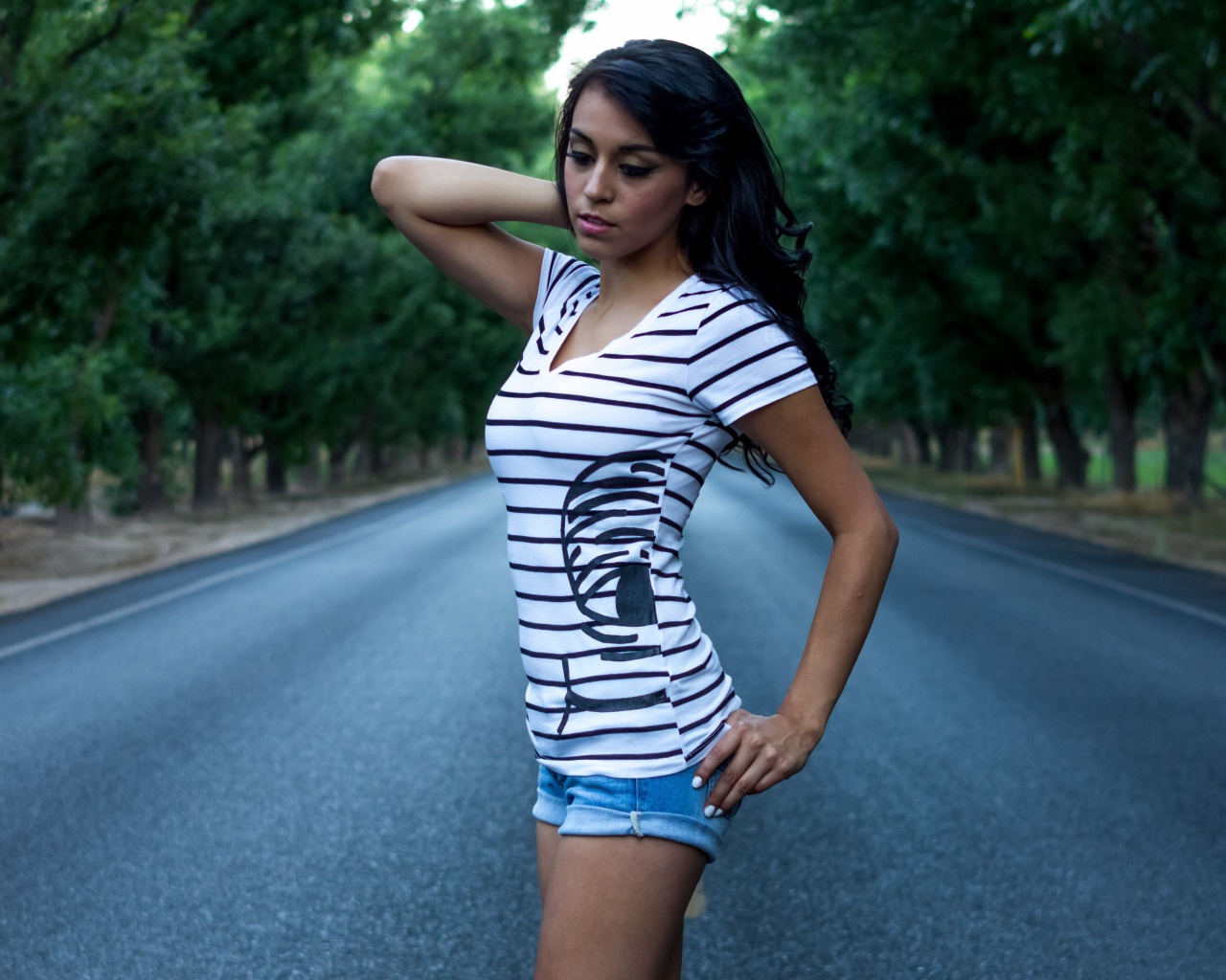 Брюнетка в джинсовых шортах среди дороги