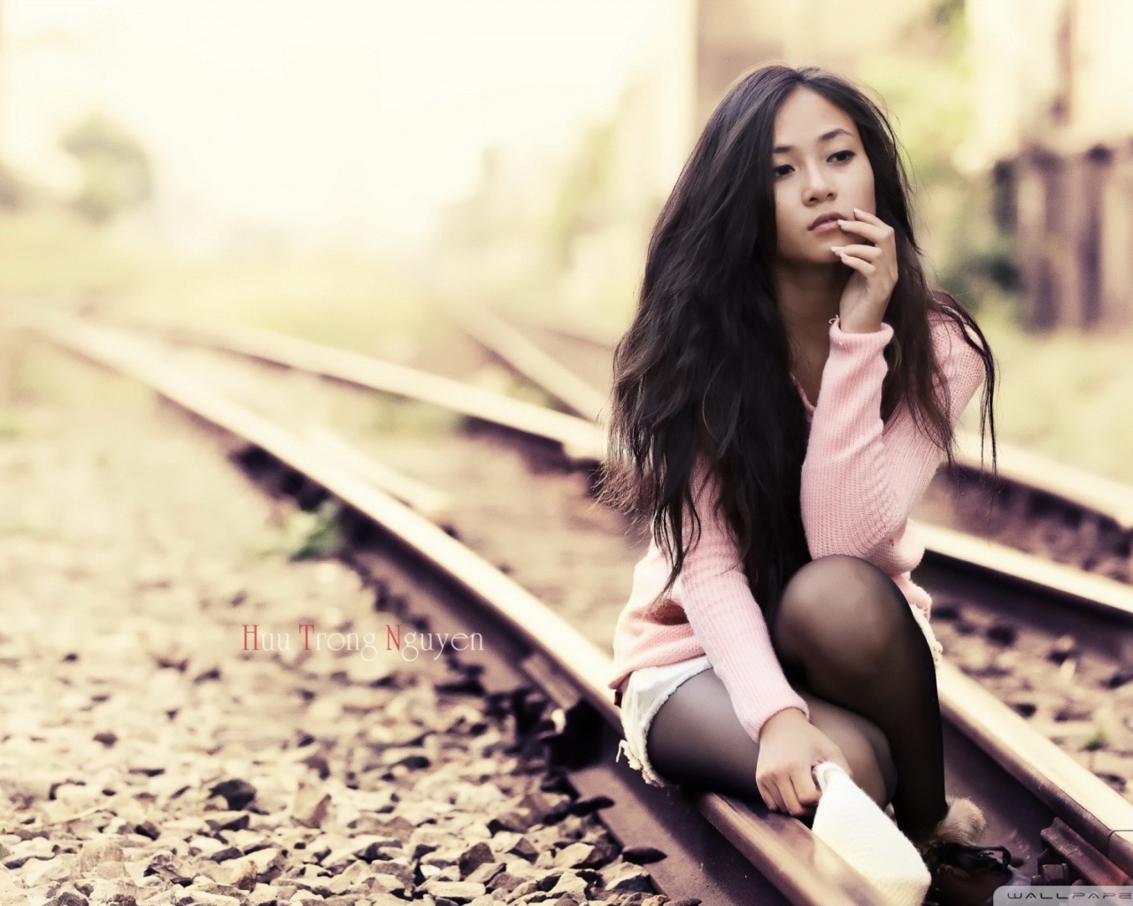 Брюнетка сидит на холодных рельсах