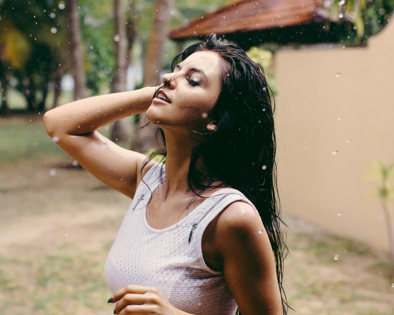 Брюнетка подставляет лицо под капли дождя