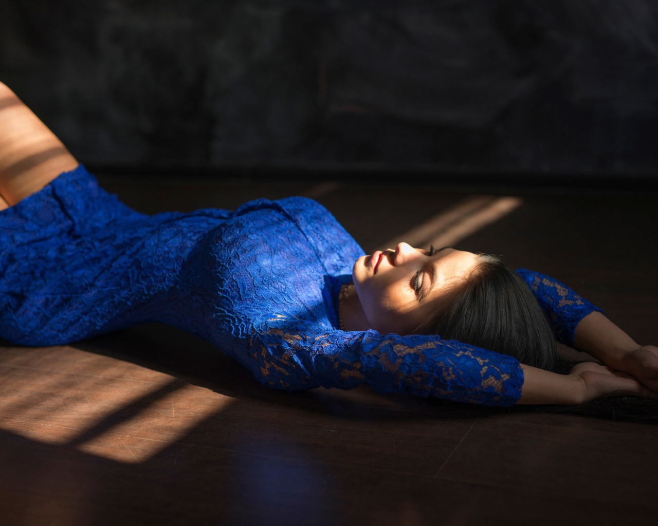 Девушка в голубом кружевном платье лежит на полу