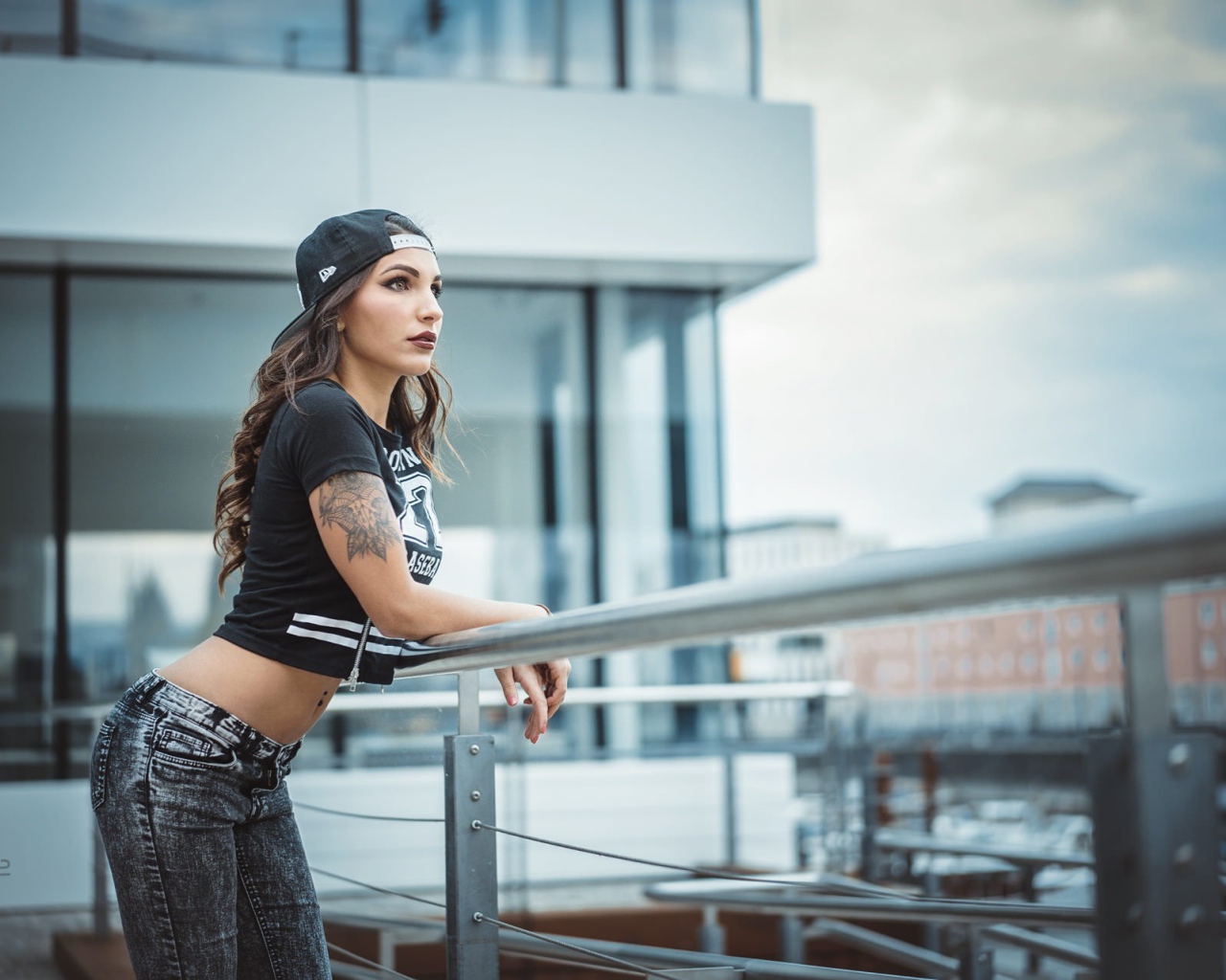 Девушка в кепке с тату смотрит на порт