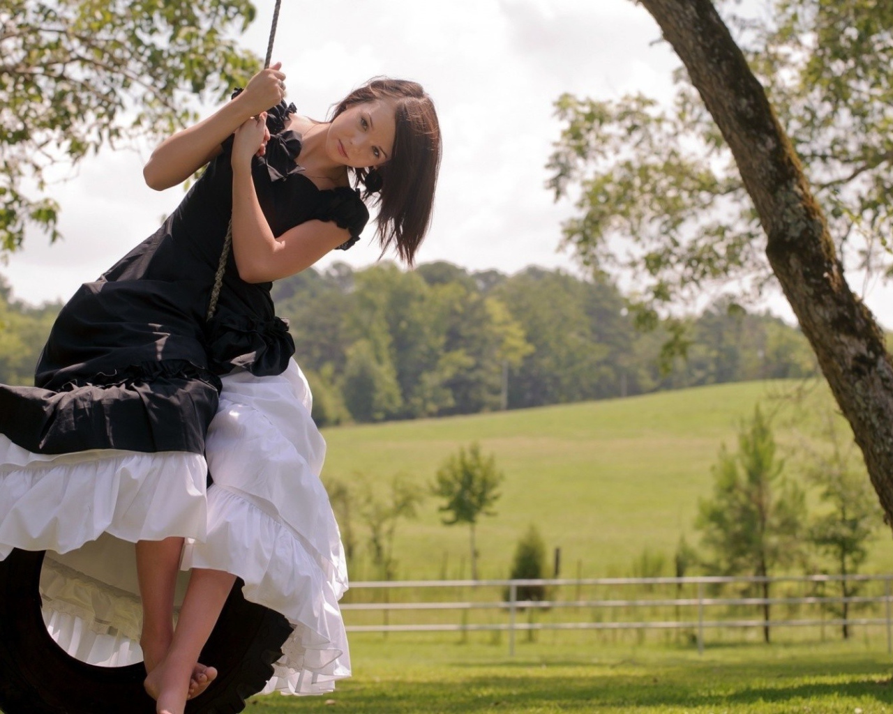 Девушка в черном платье на качелях