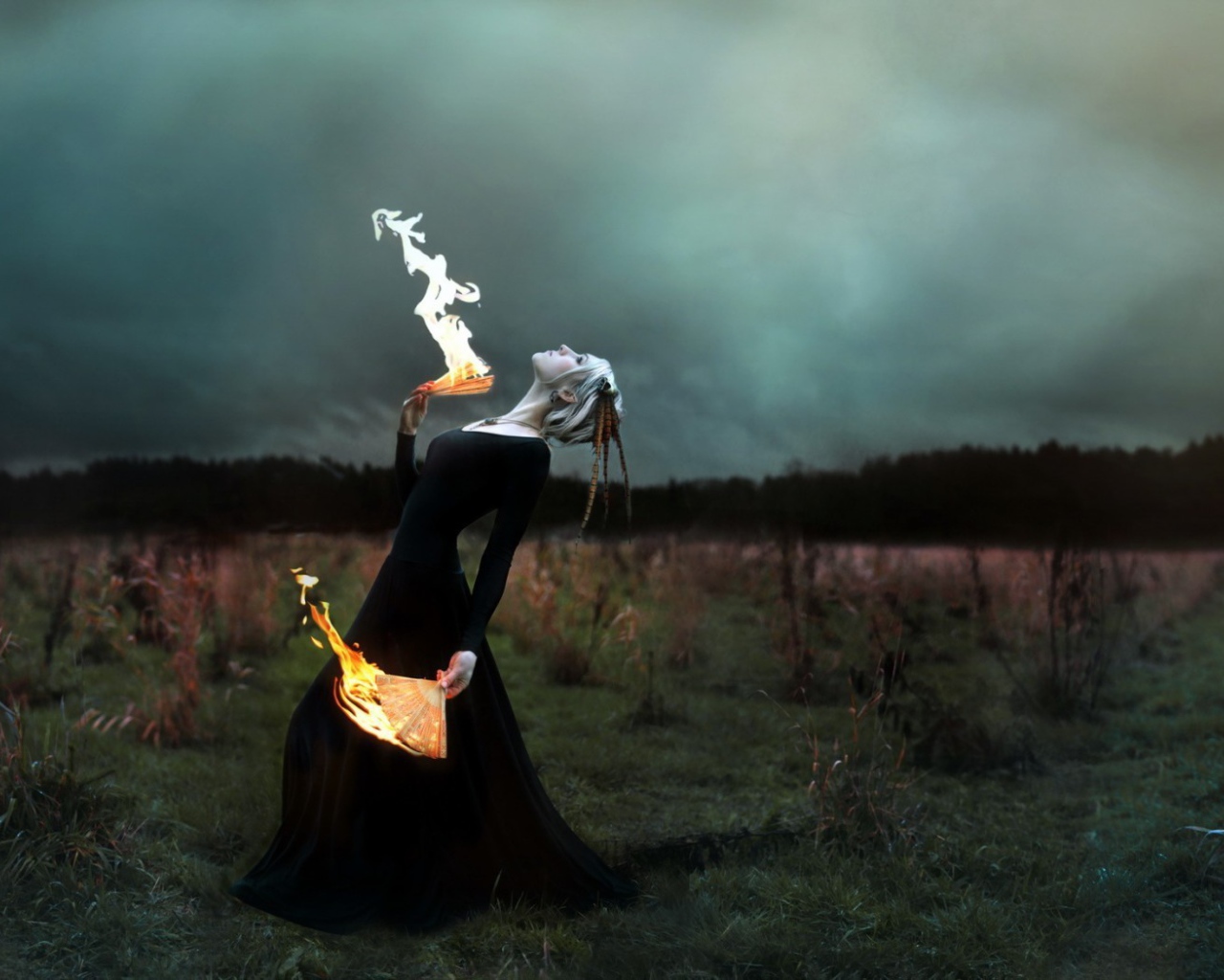 Девушка в черном платье играет с огнем