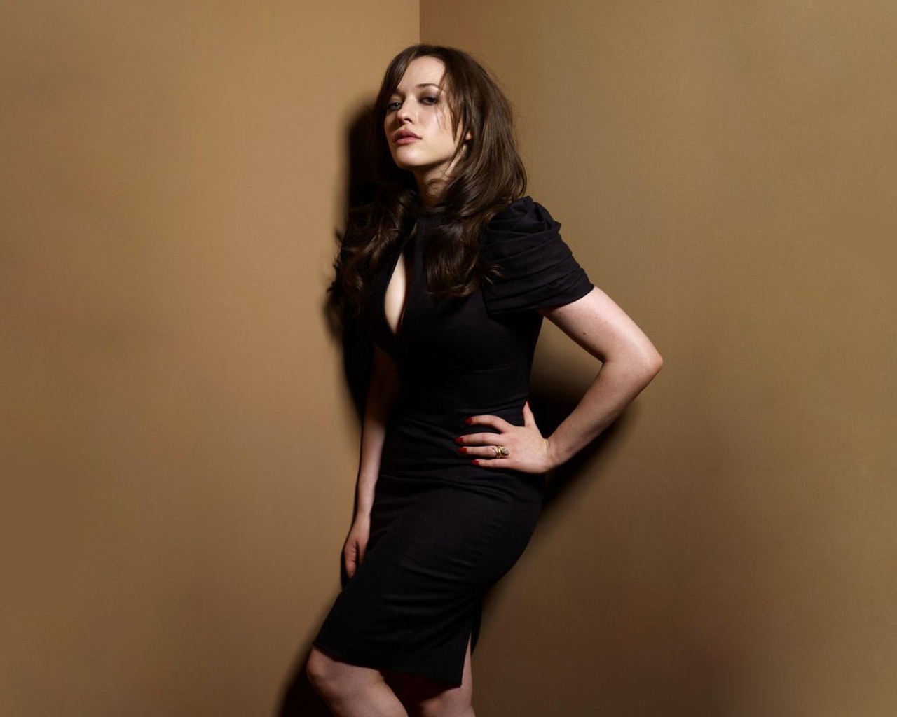 Девушка в черном платье стоит в углу