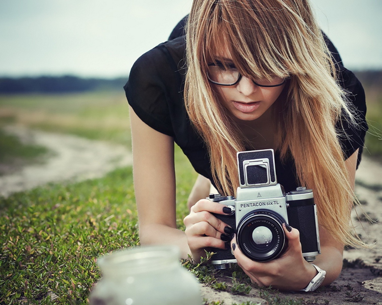 Девушка в очках фотографирует траву
