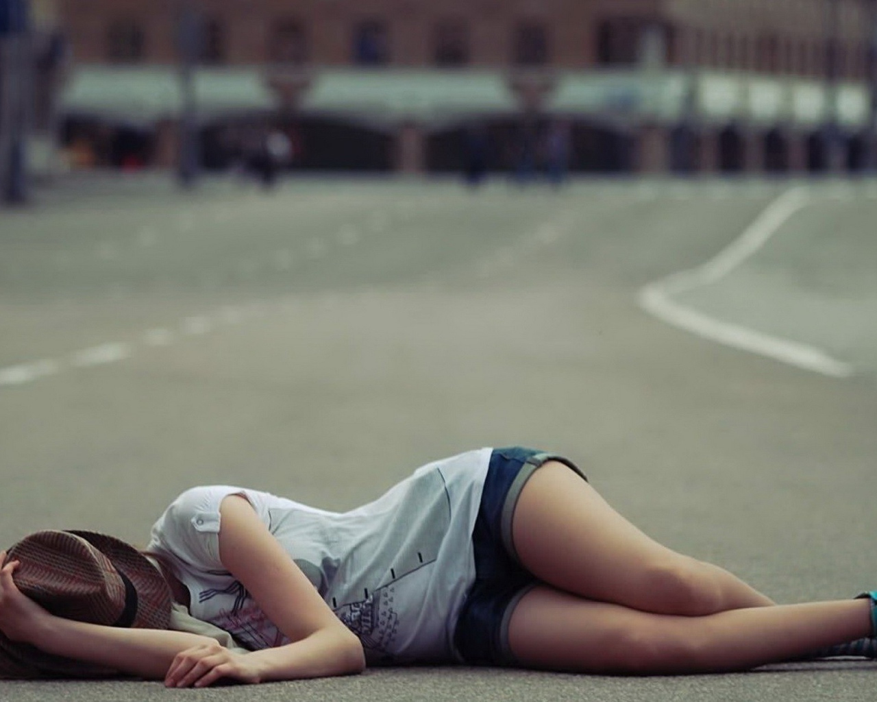 Девушка в шляпе лежит на дороге