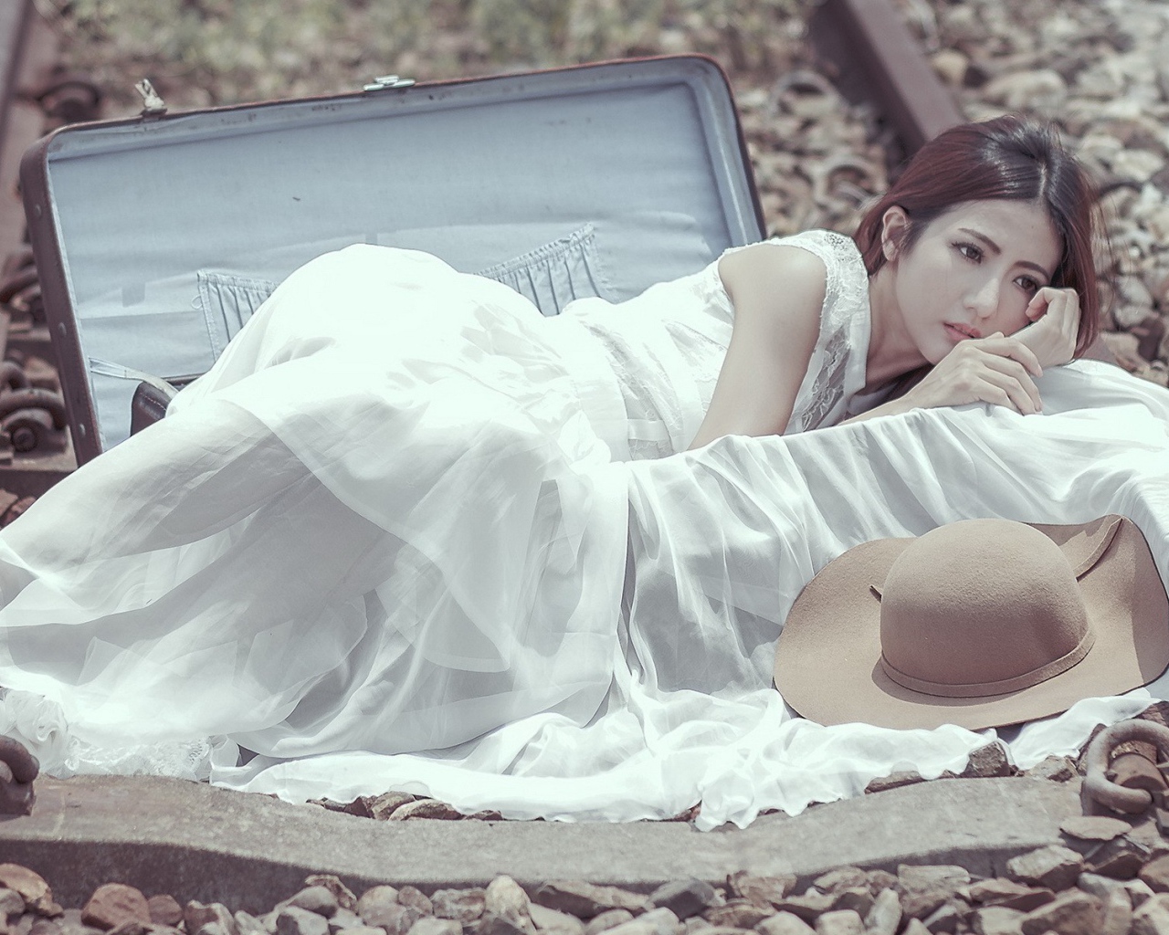 Девушка лежит в чемодане на рельсах