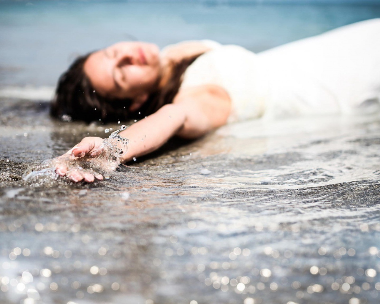 Девушка лежит в волне прибоя