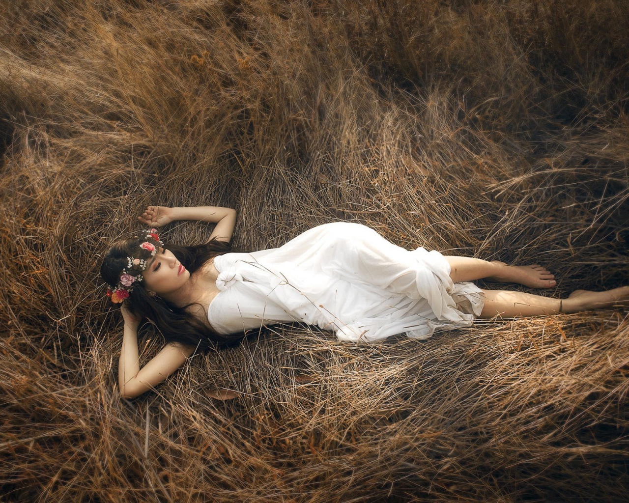 Девушка лежит на сухой траве