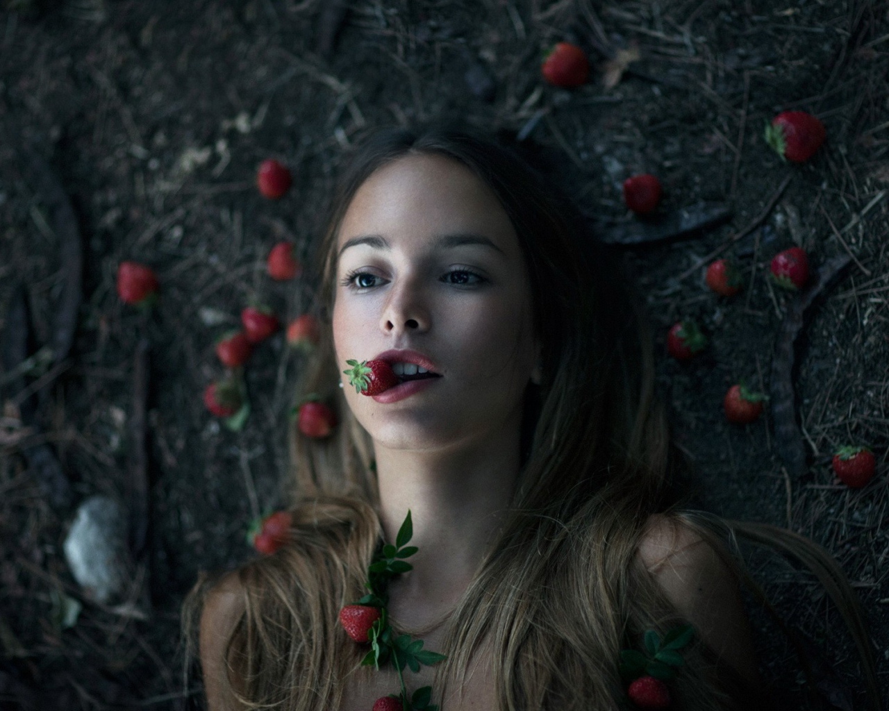 Девушка лежит на земле среди клубники