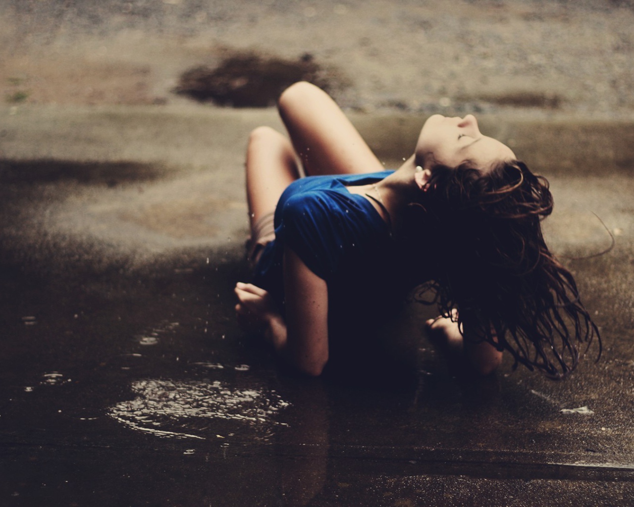 Девушка лежит на асфальте под дождем